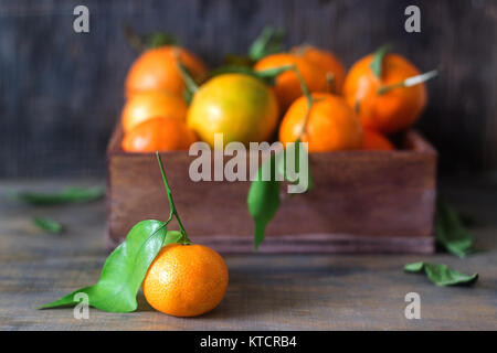 Mandarinen in einem hölzernen Kasten auf einer hölzernen Hintergrund. Rustikaler Stil, selektiven Fokus. Stockfoto