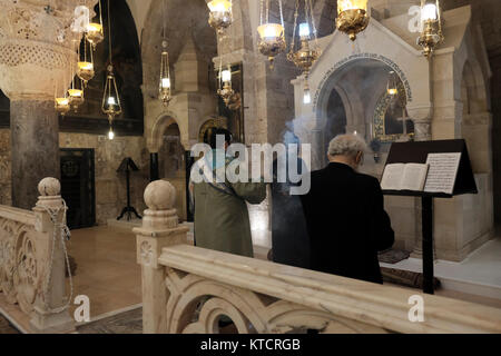 Armenisch-apostolische Priester beten vor dem Altar in der Kapelle St. Helena, die Helena, der Mutter von Kaiser Konstantin, gewidmet ist und der Überlieferung nach, die das Kreuz bei ihrem Besuch 326 n. Chr. in der Grabeskirche in der Altstadt von Jerusalem, Israel, entdeckte Stockfoto