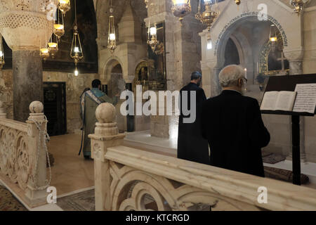 Armenisch-apostolische Priester beten vor dem Altar in der Kapelle St. Helena, die Helena, der Mutter von Kaiser Konstantin, gewidmet ist und der Überlieferung nach, die das Kreuz bei ihrem Besuch 326 n. Chr. in der Grabeskirche in der Altstadt von Jerusalem, Israel, entdeckte Stockfoto