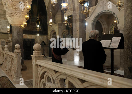 Armenisch-apostolische Priester beten vor dem Altar in der Kapelle St. Helena, die Helena, der Mutter von Kaiser Konstantin, gewidmet ist und der Überlieferung nach, die das Kreuz bei ihrem Besuch 326 n. Chr. in der Grabeskirche in der Altstadt von Jerusalem, Israel, entdeckte Stockfoto