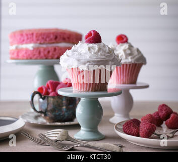 Rosa Cupcakes mit frischen Himbeeren garnieren von einem mini Kuchen Teller serviert wird. Vor einem weißen Hintergrund. Kopieren Sie Platz. Stockfoto