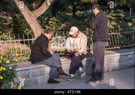 Zwei ältere Chinesen spielen Schach und ein anderes beobachten Stockfoto