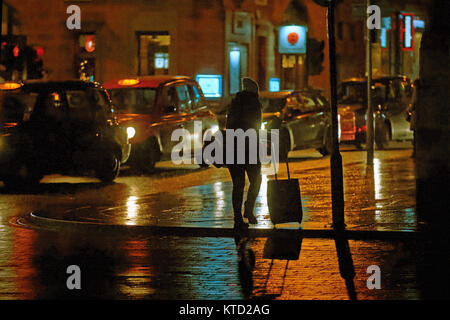 Kiesige urbanen Nacht Zeit Glasgow nasse Straße taxi Frau oder Tochter zu Hause mit Taschen Reisen Mädchen zum Busbahnhof spät in der Nacht allein in der Nähe von Stockfoto