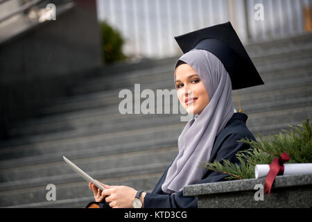 Hübsche junge weibliche Absolventin hijab tragen Stockfoto