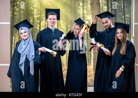 Gruppe von diversen internationalen Absolventen Feiern, Sitzen und Stehen, Konzept Stockfoto