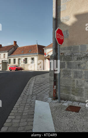 Ein rotes Auto und ein rotes Stoppschild im ruhigen Stadtzentrum von genille in das Tal der Loire in der Nähe von Nogent-le-Rotrou Frankreich. Stockfoto