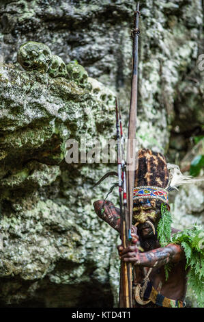 Neuguinea, Indonesien - 12. Januar: Mann mit Pfeil und Bogen. Der Krieger der Papuanischen Stamm Yafi in traditioneller Kleidung, Schmuck und Färbung. Ne Stockfoto