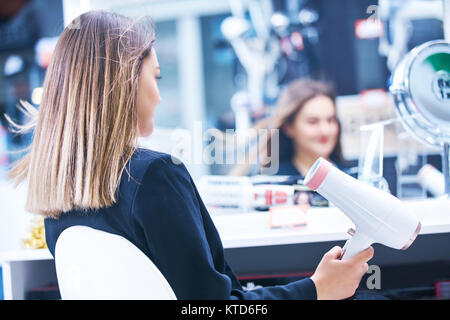 Haircare. Schöne lange behaarte Frau trocknen Haar in elektronischen Speichern Stockfoto