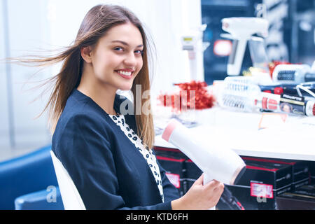 Haircare. Schöne lange behaarte Frau trocknen Haar in elektronischen Speichern Stockfoto