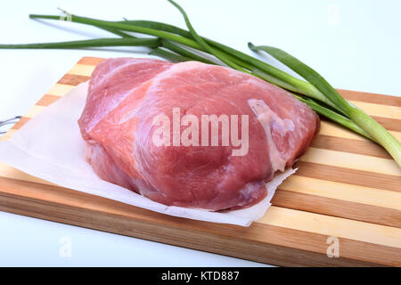 Schweinesteaks mit Fett. Fleisch ist auf Holzbrett mit Gewürze wie Pfeffer und grünen Frühlingszwiebeln. Bereit für das Kochen. Selektive konzentrieren. Stockfoto