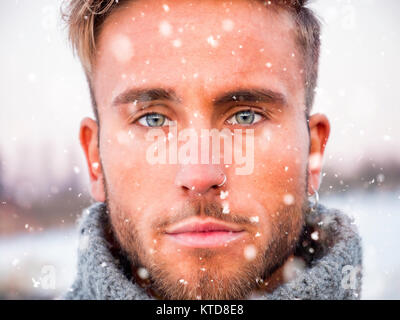 Headshot von gutaussehenden jungen Mann outdoor im Winter Mode, tragen Rollkragen-pullover duriing Schneefall Stockfoto