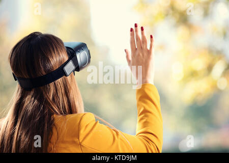 Hübsches Mädchen mit VR-Headset draußen im Park Spaß Stockfoto