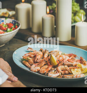 Salat, Garnelen und Kerzen auf hölzernen Tisch, quadratisch zuschneiden Stockfoto