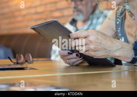 Nahaufnahme einer älteren Frau Hände, die Speisekarte im Restaurant zum Abendessen. Stockfoto