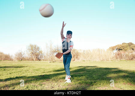 Junger Mann Werfen eines Baseballs in Park Stockfoto