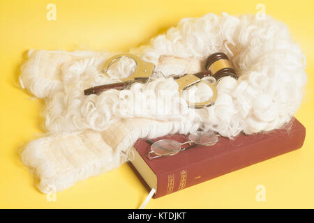 Für Richter: Richter Perücke, Handschellen, Richter Hammer, Buch Ende Brillen auf gelbem Hintergrund Stockfoto