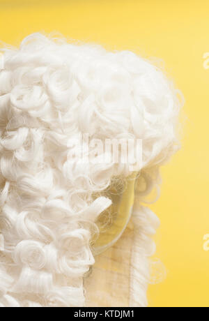 Perücke auf gelbem Hintergrund beurteilen. Stockfoto