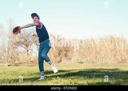 Junge Mann spielt Baseball in Park Stockfoto