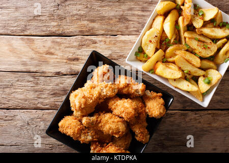 Fried Chicken Wings in Semmelbrösel und Potato Wedges schließen auf den Tisch. horizontal oben Ansicht von oben Stockfoto