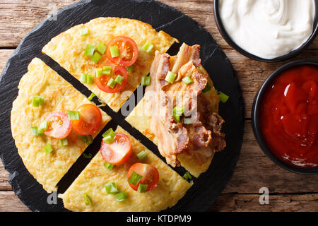 Kartoffel Boxty mit Speck, Tomaten, Zwiebeln und Sauce close-up auf dem Tisch. horizontal oben Ansicht von oben Stockfoto