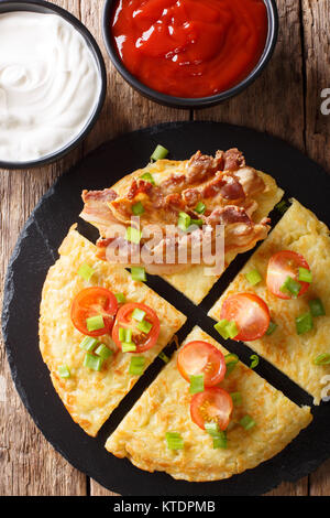 Kartoffel Boxty mit Speck, Tomaten, Zwiebeln und Sauce close-up auf den Tisch. Vertikal oben Ansicht von oben Stockfoto