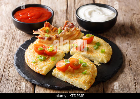 Traditionelle Boxty Kartoffelpuffer mit Speck, Tomaten, Zwiebeln und Saucen close-up auf dem Tisch. Horizontale Stockfoto