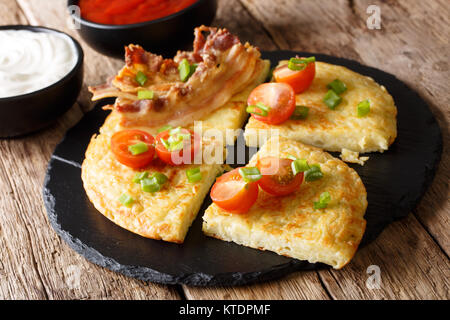 Kartoffel Boxty mit Speck, Tomaten, Zwiebeln und Sauce close-up auf dem Tisch. Horizontale Stockfoto