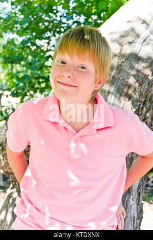 Lächelnde Junge in rosa Hemd in der Nähe von Tree Stockfoto