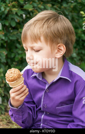 Vertikale Foto des blonden Jungen essen Eis im Sommer Stockfoto