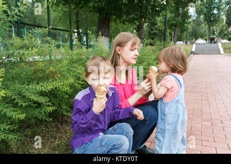 Mutter mit Jungen und Mädchen im Sommer Park essen Eis sitzen Stockfoto