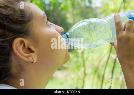 Close-up junge Frau in Wasser aus Kunststoff Flasche in den Wald. Stockfoto