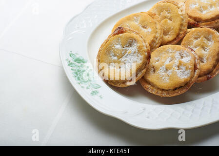 Hausgemachte Weihnachten Mince Pies auf einem weißen klassische Platte über einen Tisch mit weißer Tischdecke. Stockfoto
