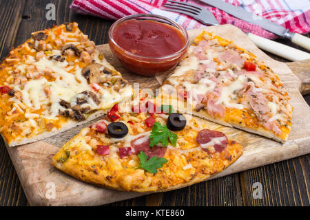 Drei Stücke von verschiedenen Pizzen auf Holz. Studio Foto Stockfoto