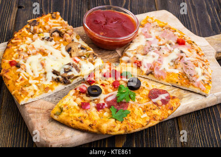 Drei Stücke von verschiedenen Pizzen auf Holz. Studio Foto Stockfoto