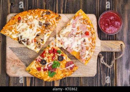 Drei Stücke von verschiedenen Pizzen auf Holz. Studio Foto Stockfoto