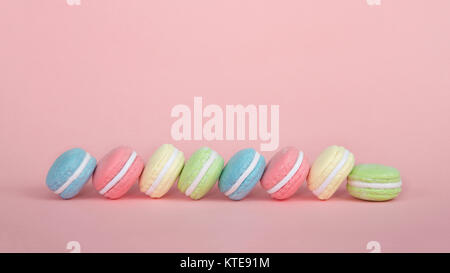 Große Macaroon Cookies in Kristallzucker auf einem Tisch abwechselnden Farben abgedeckt. rosa Hintergrund. Beliebte Gebäck in Frankreich. Stockfoto