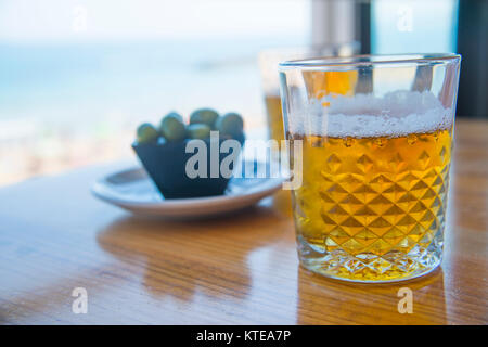 Zwei Gläser Bier und Tapas der grüne Oliven in den Strand. Santander, Spanien. Stockfoto