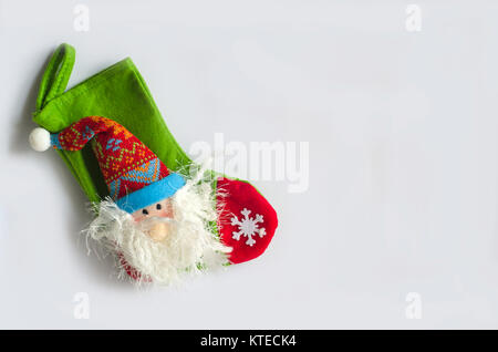 Weihnachtsdekoration auf weißem Hintergrund. Weihnachten Santa Socke mit einer Figur und Schneeflocken. Stockfoto