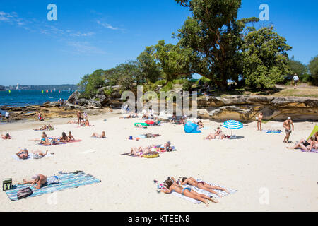 Junge Leute, die sich am Balmoral Edwards Beach in Mosman Sydney, New South Wales, Australien neben Rocky Point Island entspannen und sonnen Stockfoto