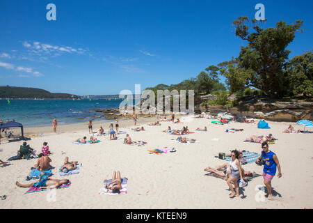 Junge Leute, die sich am Balmoral Edwards Beach in Mosman Sydney, New South Wales, Australien neben Rocky Point Island entspannen und sonnen Stockfoto