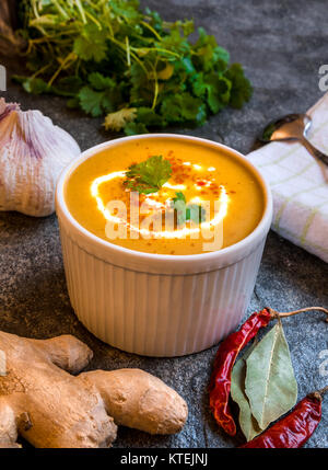 Pikant vegetarisch/vegan butternut Kürbis Suppe serviert in der Schüssel am Tisch aus Stein durch frische Zutaten umgeben Stockfoto