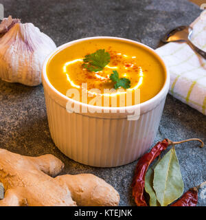 Nahaufnahme von butternut Kürbis Suppe in Schüssel auf steinernen Tisch mit frischen Zutaten umgeben Stockfoto