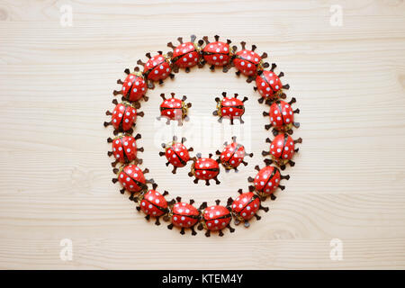 Grußkarte mit einem Smiley, gebildet durch Schokolade Marienkäfer, auf hellem Holz Stockfoto