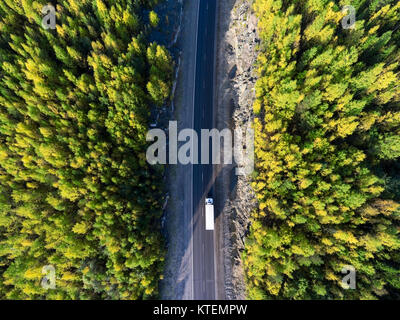 Top Blick auf weiße Fracht Lkw fahren zwischen Rock Tunnel in goldener Herbst Wälder von Karelien, Russland Stockfoto