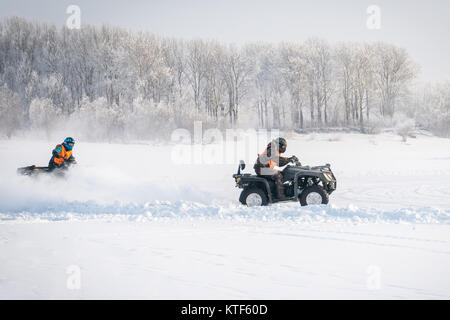 Nicht identifizierte Motocross Fahrer auf Quad Motocross saison Rennen zu öffnen. winter Motocross. ATVs sind Reiten in das Feld im Schnee auf der backgrou Stockfoto