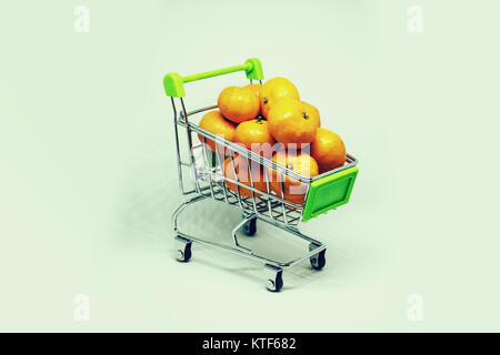 Miniatur Warenkorb mit Mandarinen auf weißem Hintergrund. Kauf von Obst. Korb mit reifem Miniatur Apfelsinensorten. Kauf von Obst im Supermarkt. ma Stockfoto