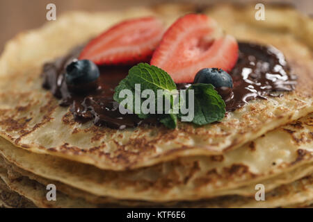 Stapel Pfannkuchen mit Beeren und dunkler Schokolade auf der Oberseite gegossen Stockfoto