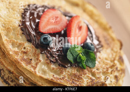 Stapel Pfannkuchen mit Beeren und dunkler Schokolade auf der Oberseite gegossen Stockfoto