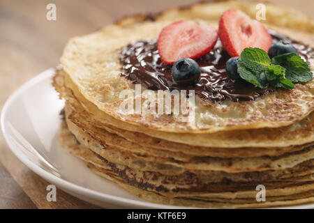 Stapel Pfannkuchen mit Beeren und dunkler Schokolade auf der Oberseite gegossen Stockfoto