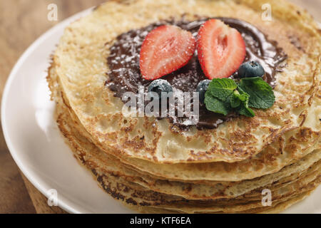 Stapel Pfannkuchen mit Beeren und dunkler Schokolade auf der Oberseite gegossen Stockfoto